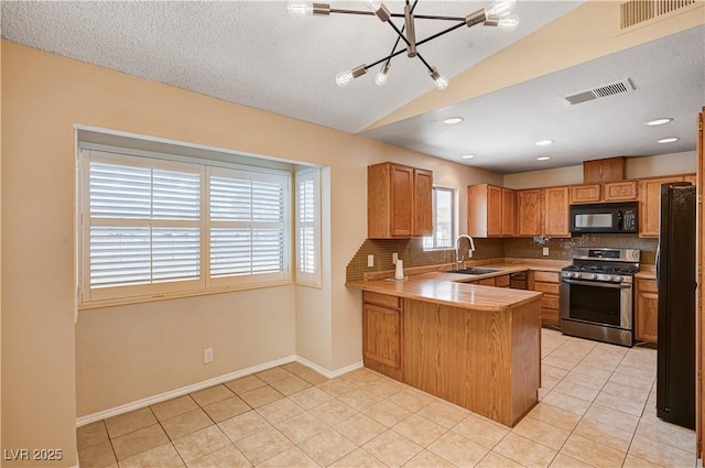 kitchen with a sink, visible vents, black appliances, and a peninsula