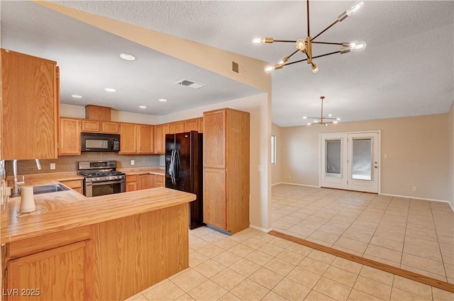 kitchen featuring visible vents, light tile patterned floors, a notable chandelier, black appliances, and a sink