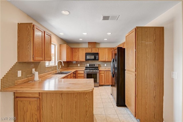 kitchen featuring visible vents, light countertops, a peninsula, black appliances, and a sink