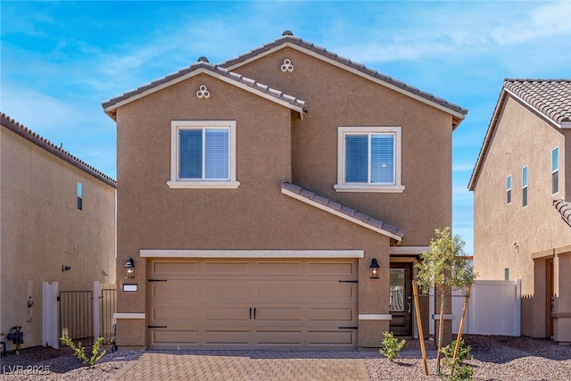 view of front facade featuring a tile roof, an attached garage, fence, decorative driveway, and stucco siding