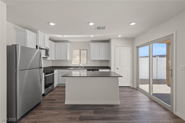 kitchen with appliances with stainless steel finishes, dark countertops, visible vents, and white cabinets