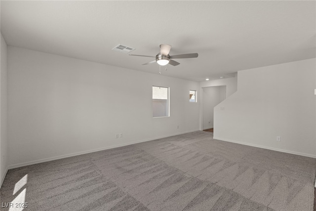 carpeted empty room featuring ceiling fan, visible vents, and baseboards