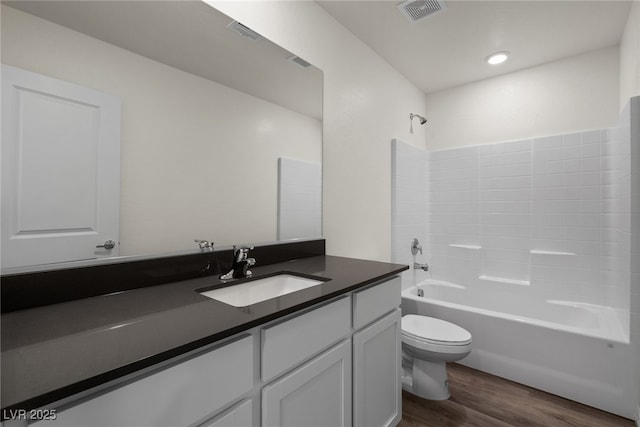 bathroom with toilet, wood finished floors, visible vents, vanity, and bathing tub / shower combination