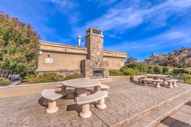 view of patio featuring outdoor dining space, an outdoor stone fireplace, and fence