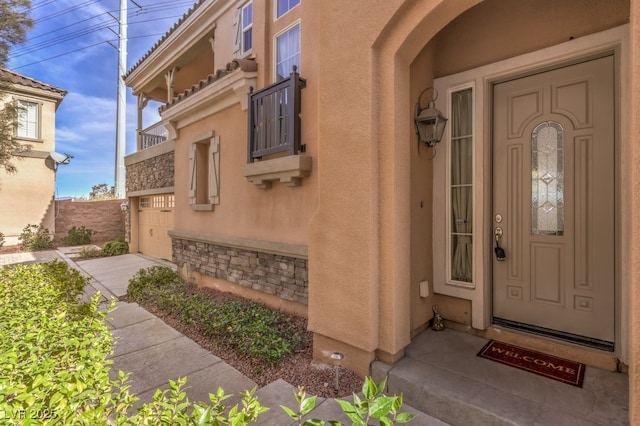 view of exterior entry with stone siding and stucco siding