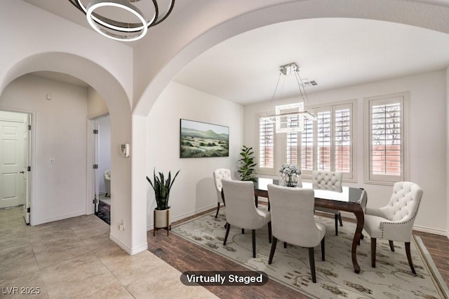 dining space with arched walkways, baseboards, visible vents, and a notable chandelier