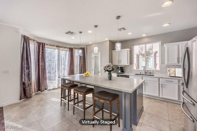 kitchen with a center island, visible vents, a sink, and freestanding refrigerator