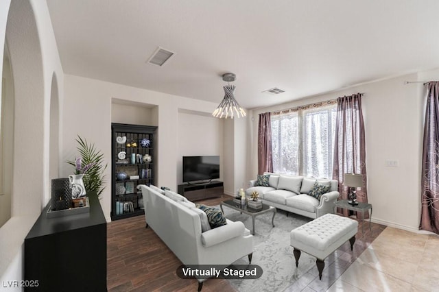 living area with baseboards, visible vents, arched walkways, and wood finished floors