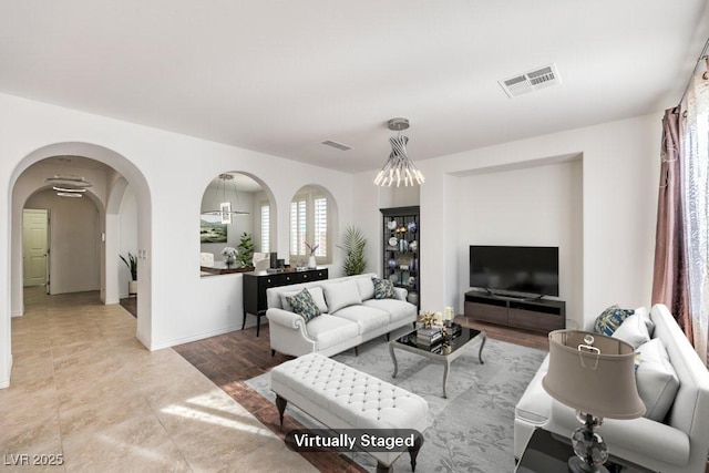 living room with baseboards, visible vents, and arched walkways