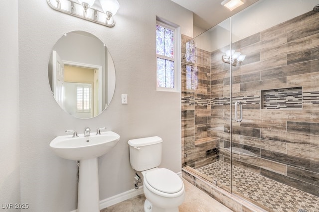 full bath featuring a stall shower, baseboards, a sink, and toilet