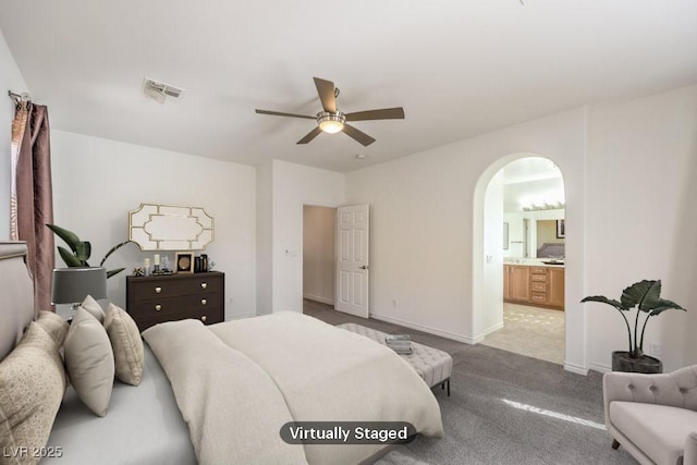 bedroom featuring arched walkways, connected bathroom, light colored carpet, visible vents, and baseboards