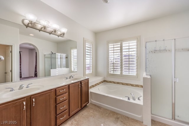 bathroom featuring a bath, a stall shower, double vanity, and a sink