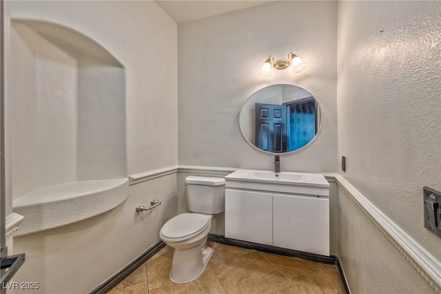 half bath with toilet, tile patterned flooring, and vanity