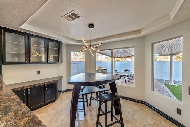 dining room with a wealth of natural light, a tray ceiling, visible vents, and baseboards