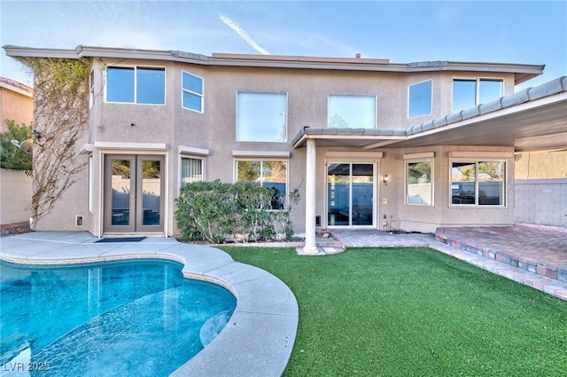 back of property featuring french doors, a patio area, a lawn, and stucco siding