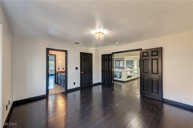 spare room with baseboards, visible vents, and dark wood finished floors