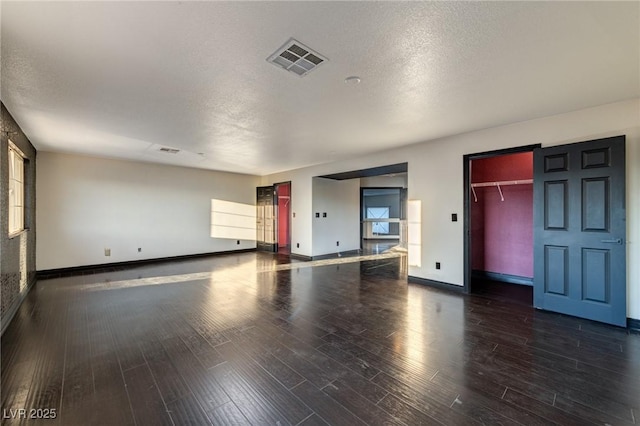 unfurnished living room featuring a textured ceiling, wood finished floors, visible vents, and baseboards