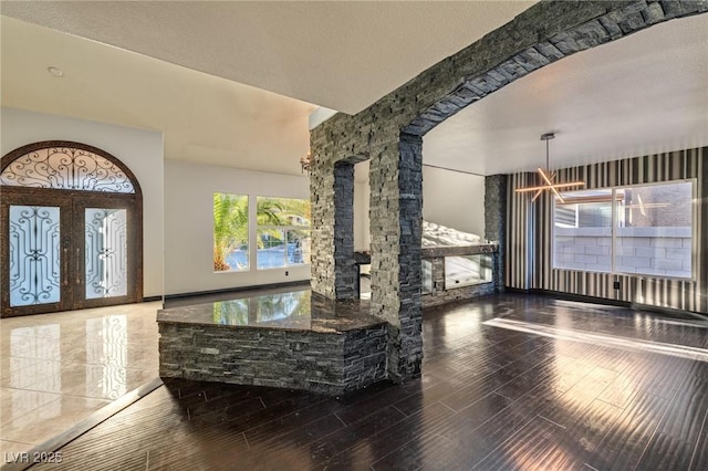 foyer entrance with a chandelier, french doors, a textured ceiling, and wood finished floors