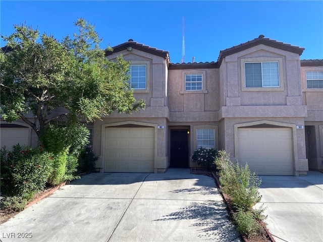 townhome / multi-family property featuring driveway, an attached garage, a tile roof, and stucco siding