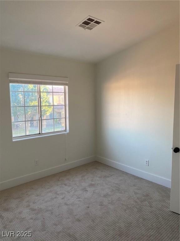 empty room with baseboards, visible vents, and light colored carpet