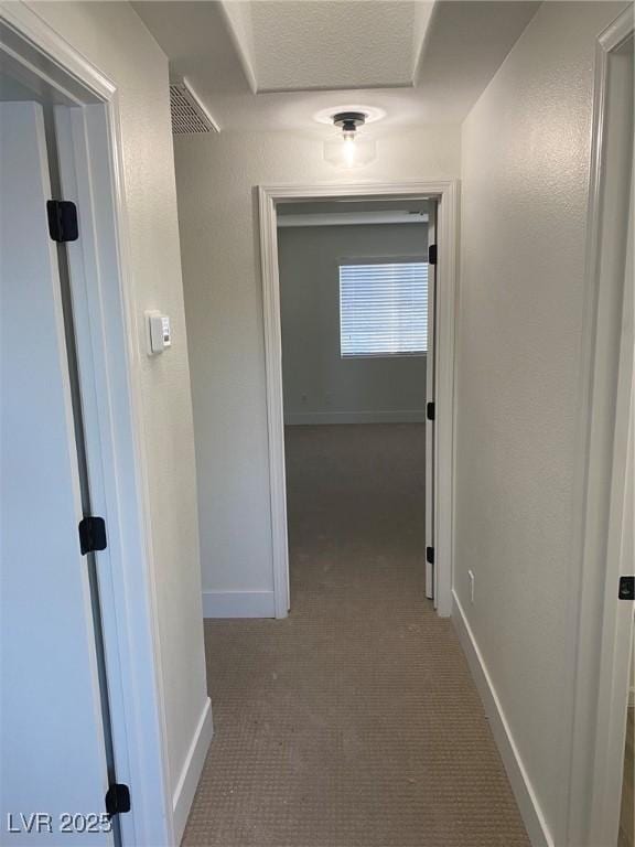 hall featuring visible vents and baseboards