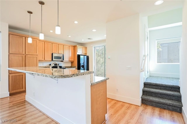 kitchen featuring light stone countertops, light wood finished floors, stainless steel appliances, and recessed lighting