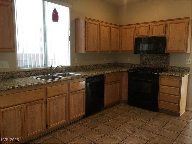 kitchen featuring brown cabinetry, pendant lighting, a sink, and black appliances