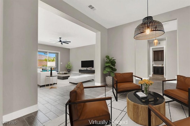 living room with ceiling fan, light wood-style flooring, visible vents, and baseboards