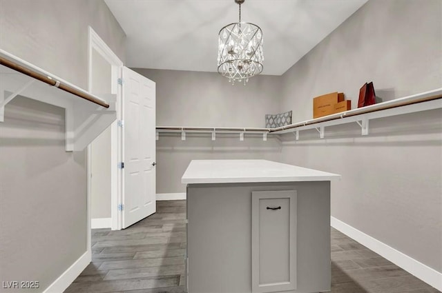 spacious closet with an inviting chandelier and dark wood-type flooring