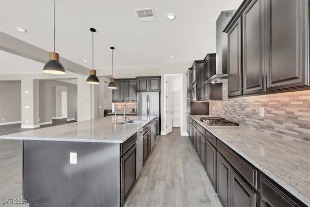 kitchen featuring light stone counters, light wood-style flooring, visible vents, appliances with stainless steel finishes, and backsplash