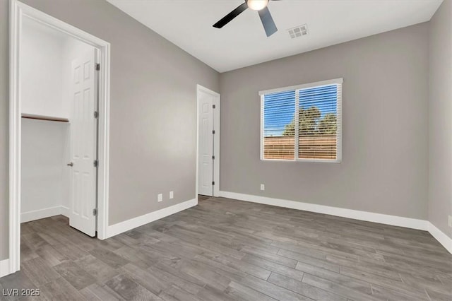 unfurnished bedroom with visible vents, baseboards, a ceiling fan, wood finished floors, and a closet