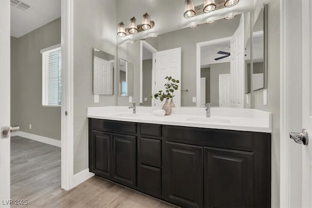 bathroom with visible vents, a sink, baseboards, and wood finished floors