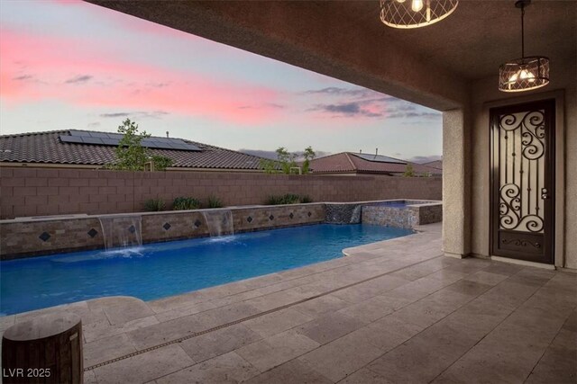 pool at dusk with a fenced in pool, a patio area, a fenced backyard, and an in ground hot tub