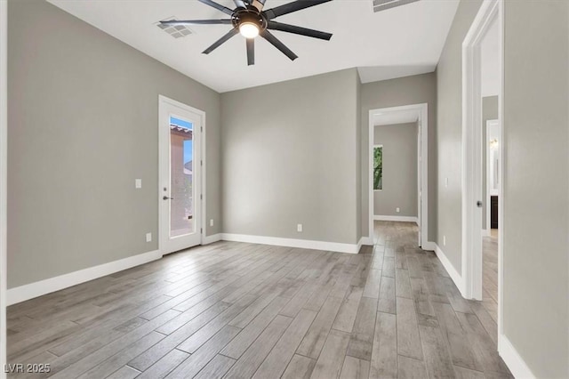 unfurnished room featuring a healthy amount of sunlight, visible vents, and wood finished floors