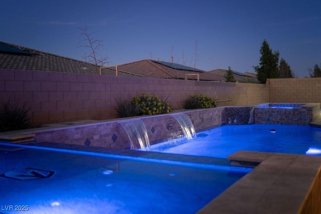 view of pool with a fenced backyard and a pool with connected hot tub