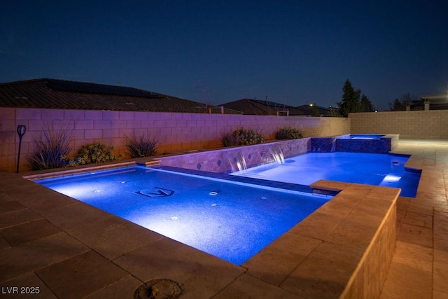 pool at twilight featuring a fenced backyard and a pool with connected hot tub