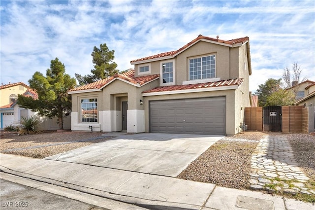 mediterranean / spanish home featuring a tile roof, a gate, concrete driveway, and stucco siding