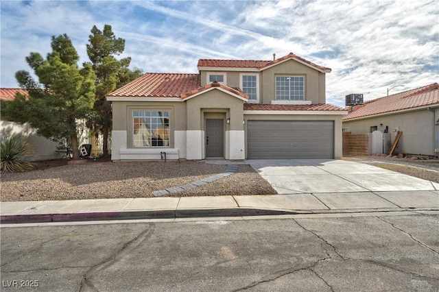 view of front of house with a garage, fence, driveway, a tiled roof, and stucco siding