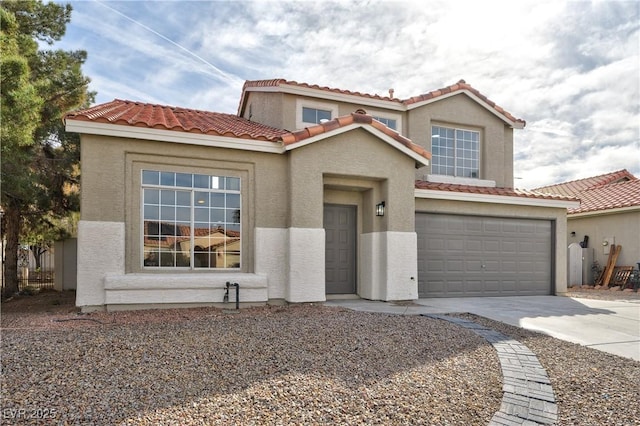 mediterranean / spanish home featuring an attached garage, a tiled roof, concrete driveway, and stucco siding