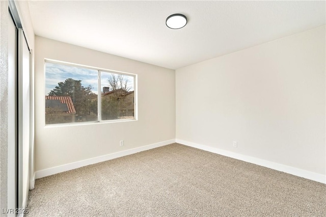 spare room featuring carpet and baseboards