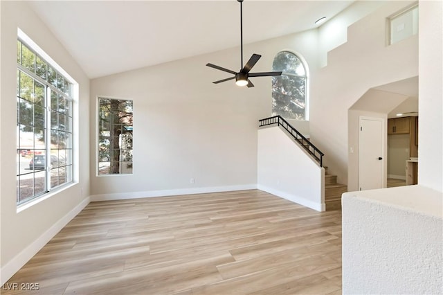 unfurnished living room featuring light wood-type flooring, a wealth of natural light, stairway, and baseboards