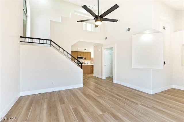 unfurnished living room featuring visible vents, ceiling fan, light wood-style flooring, and baseboards