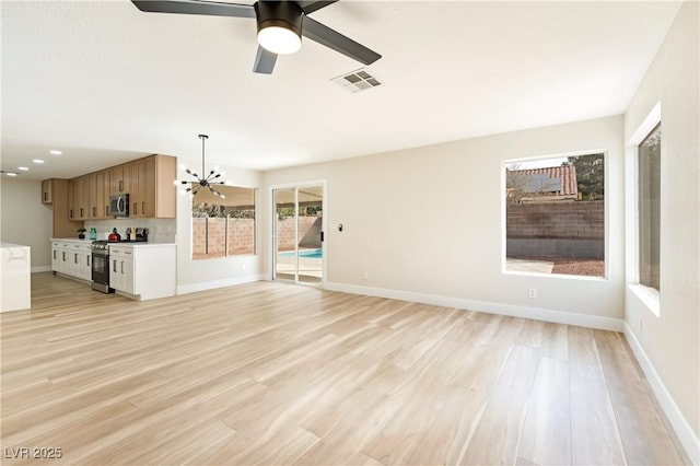 unfurnished living room featuring baseboards, visible vents, light wood finished floors, and ceiling fan with notable chandelier