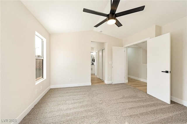 empty room featuring vaulted ceiling, ceiling fan, baseboards, and light colored carpet