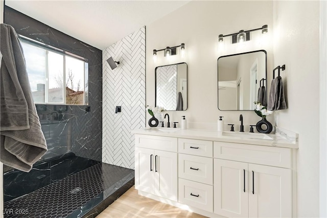 bathroom featuring double vanity, a marble finish shower, and a sink