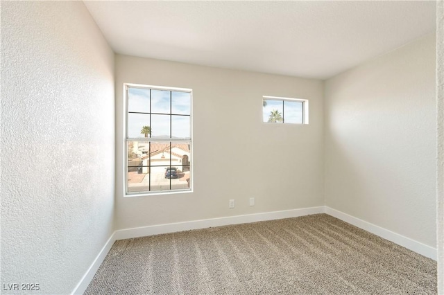 carpeted spare room with a textured wall and baseboards