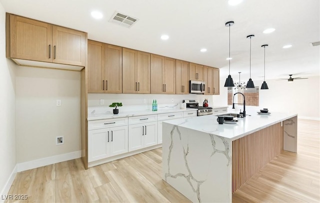 kitchen with stainless steel appliances, visible vents, a sink, and light wood finished floors