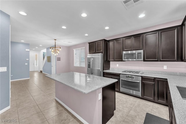 kitchen with light tile patterned floors, stainless steel appliances, visible vents, dark brown cabinetry, and a kitchen island