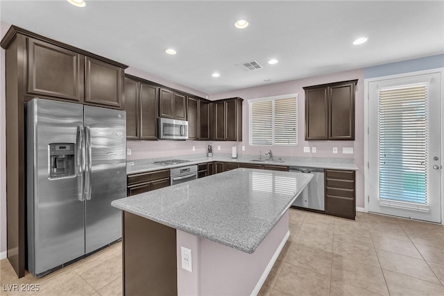 kitchen with dark brown cabinetry, light tile patterned floors, visible vents, appliances with stainless steel finishes, and a center island