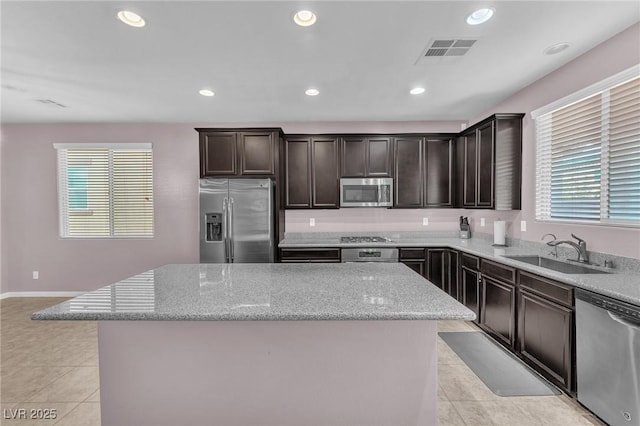 kitchen with light tile patterned floors, visible vents, a center island, stainless steel appliances, and a sink